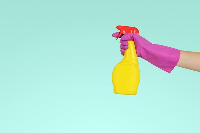 hand wearing gloves with a spray cleaner